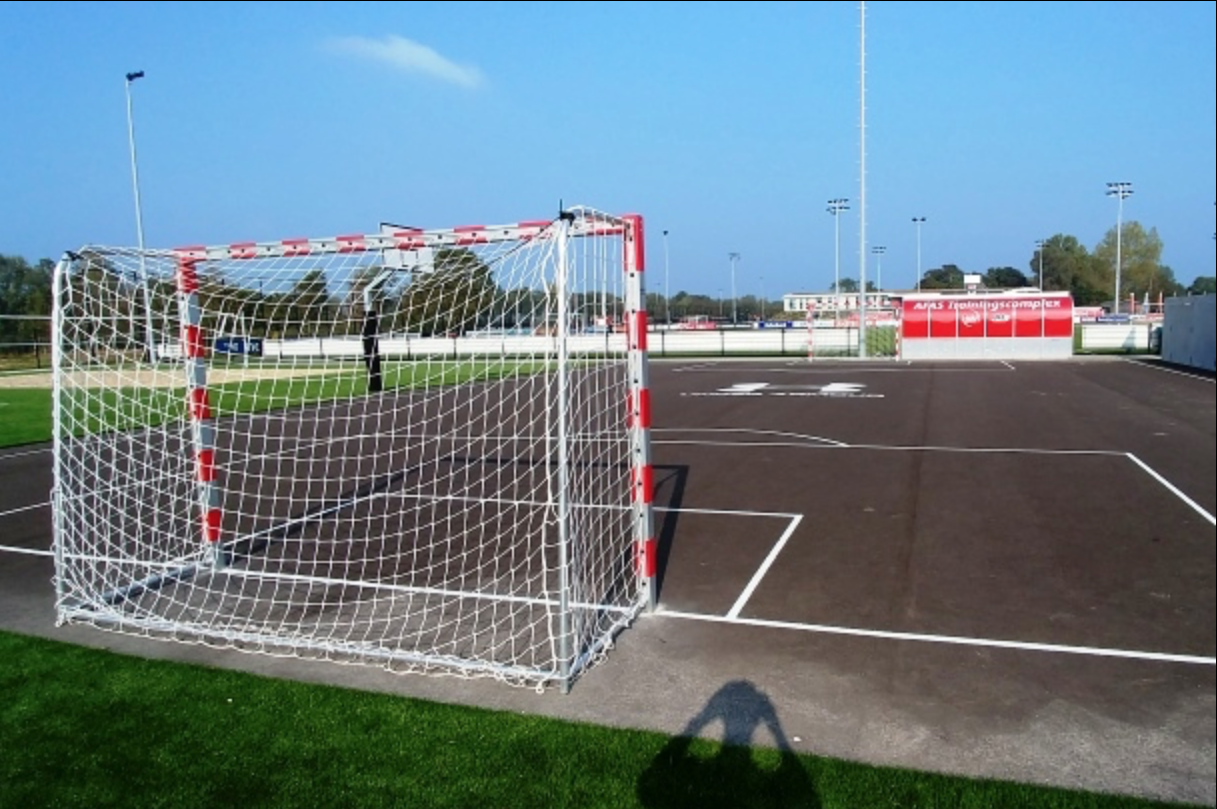 Asphalt pitch with two goals and a basketball hoop